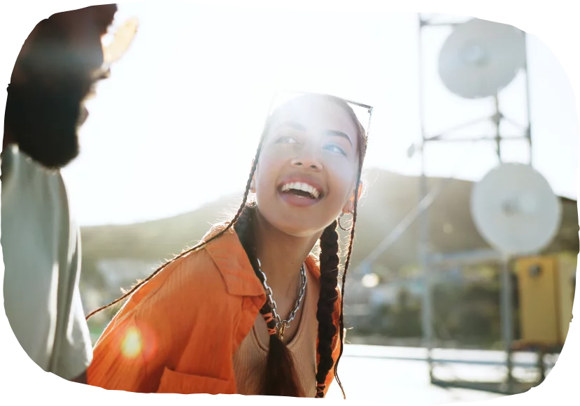 Young Black woman looks to her friend with the sun shining in the background