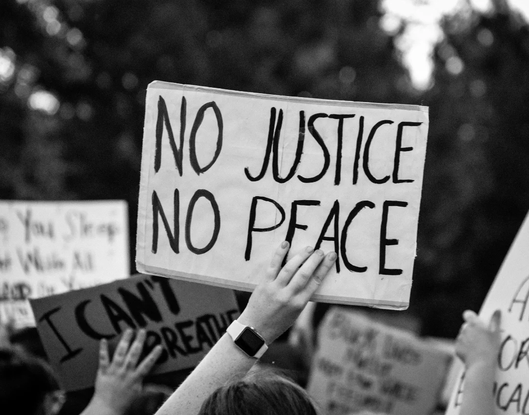 Black and white photo of a protest sign that reads No Justice No Peace