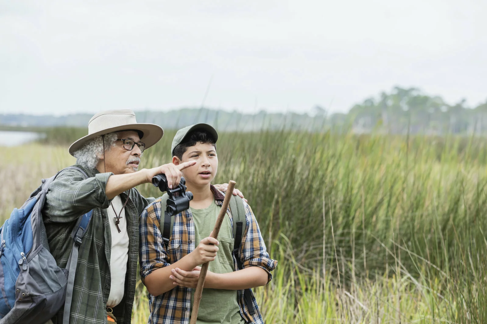 Latine boy hiking with grandfather, bird watching